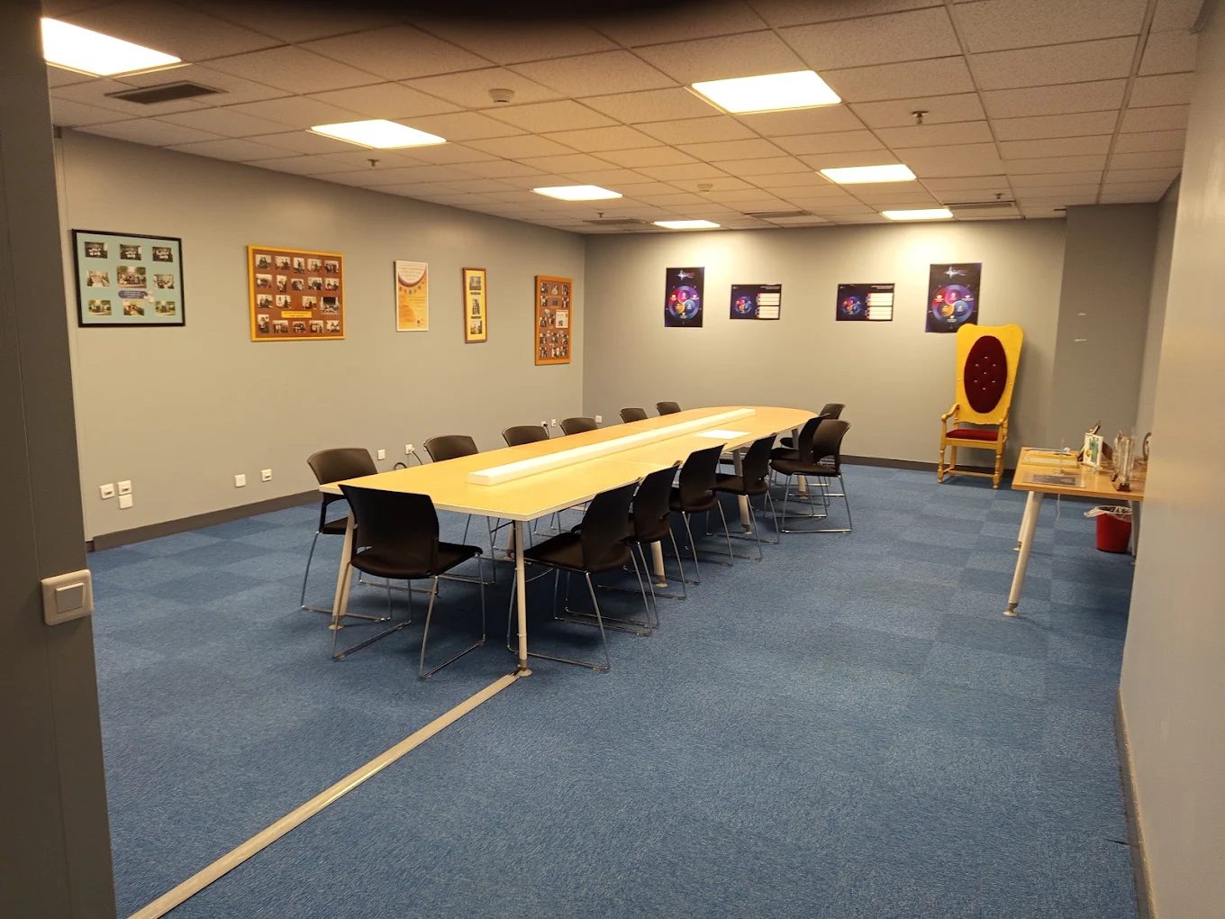 Salle de réunion remise en ordre : grande table centrale, chaises alignées et moquette bleue nettoyée